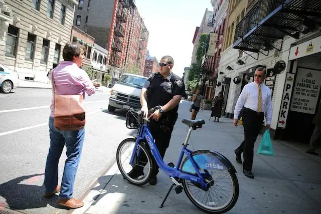 Officer Simunovic of the Ninth Precinct points to the "Rules of the Road" posted on every Citi Bike for the cyclist's benefit, shortly after ticketing him for running a red light